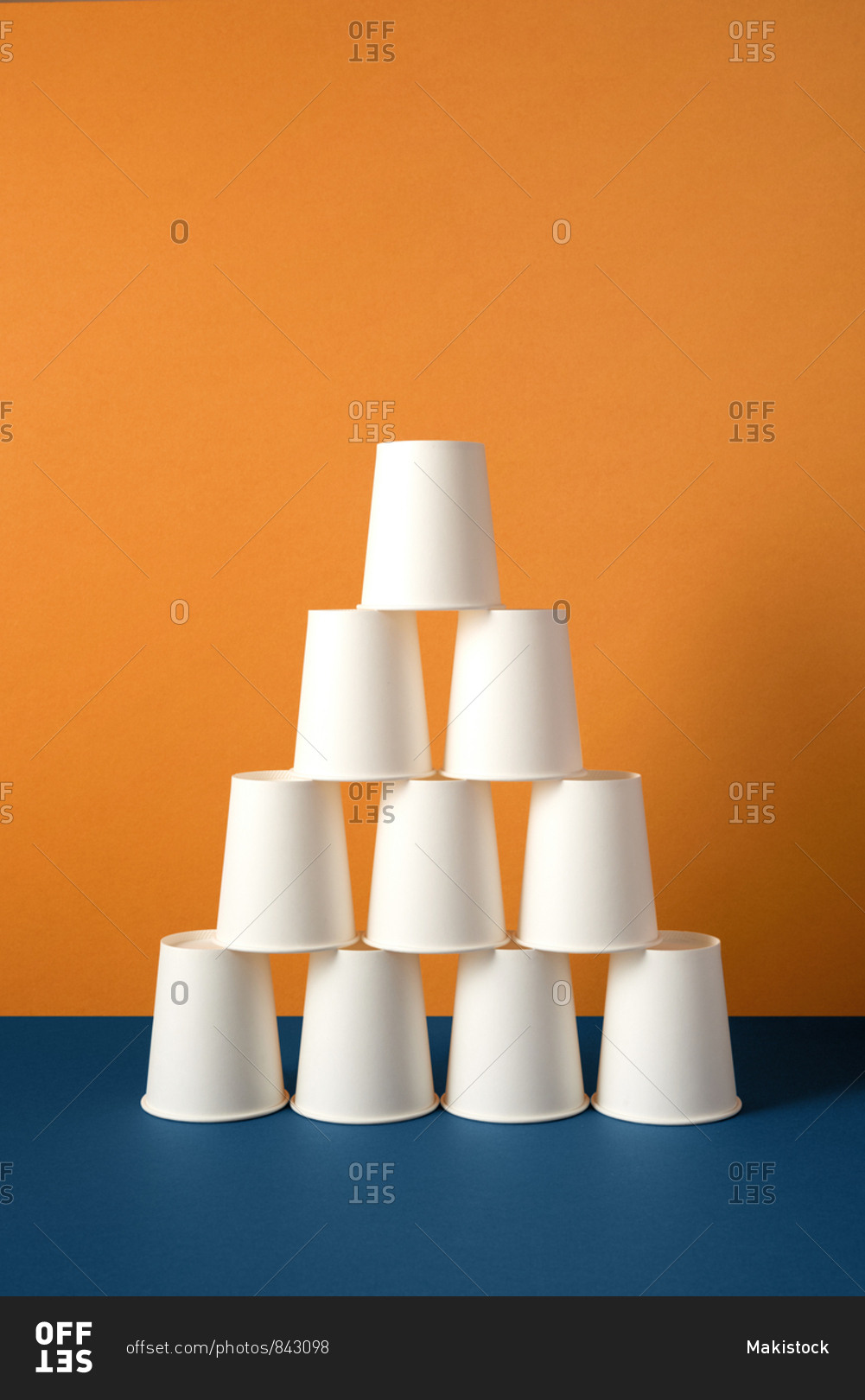 Disposable plastic white empty cups on blue and orange background