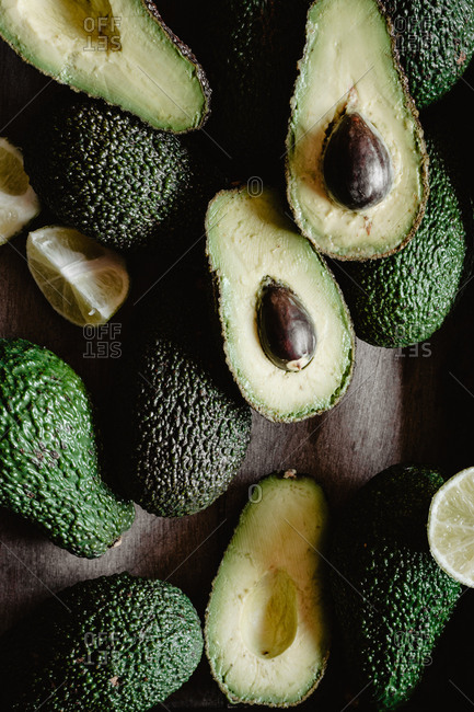 Closeup photo of raw whole and sliced avocados in a wooden box.