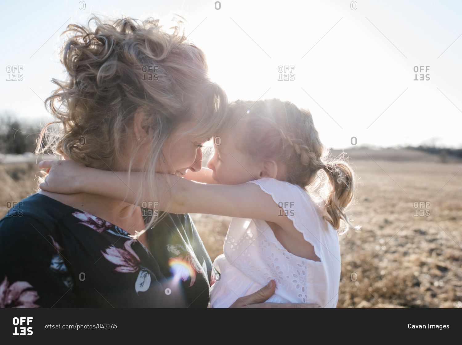 Mother and daughter in summer dresses laughing and smiling at sunset