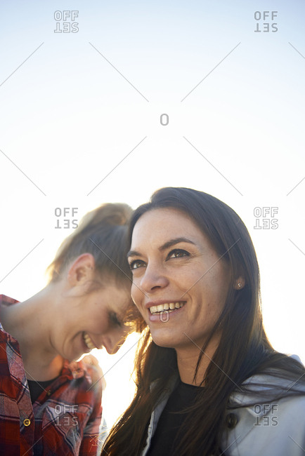 Happy lesbian couple looking away against clear sky during sunset