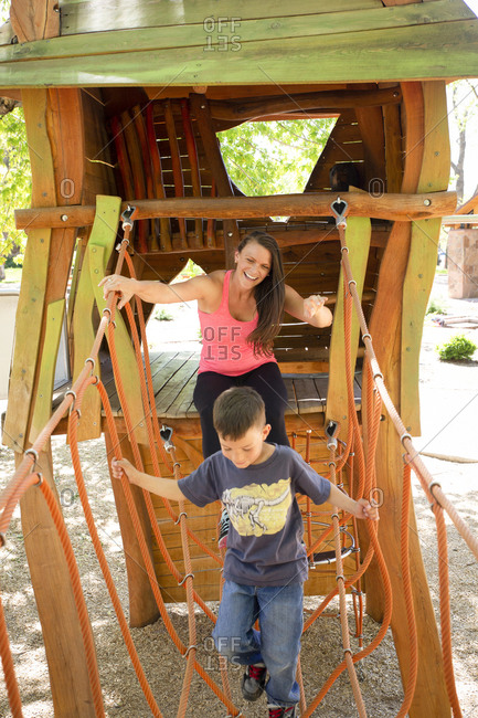 Happy mother and son playing on outdoor play equipment at playground