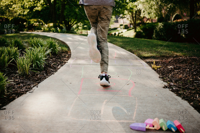 Girl playing hopscotch on sidewalk
