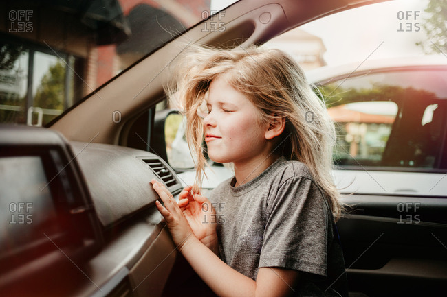 Girl cooling off inside a car with air conditioning