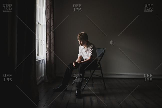 Portrait of a well dressed tween sitting in folding chair by window