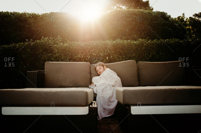 Young girl relaxing on outdoor sofa after a swim