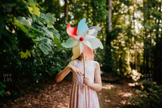 Girl in the forest spinning a pinwheel in front of her face