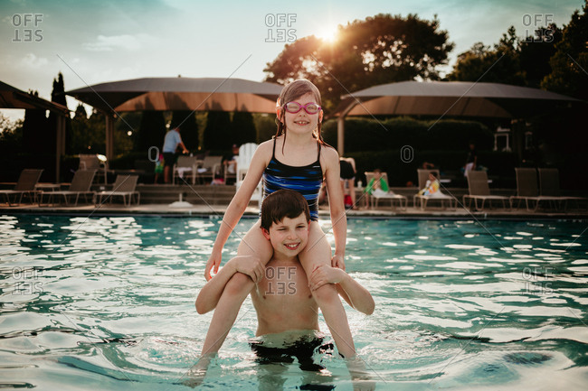 Girl sitting on boy's shoulders in pool