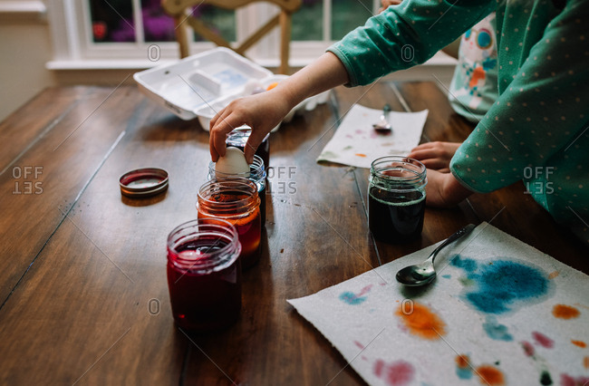 Girls dyeing Easter eggs on wooden table