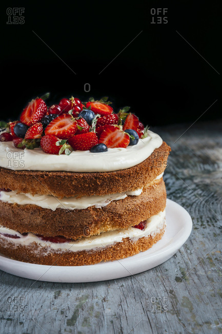 Forest fruit nude cake on a wooden surface in front of dark background