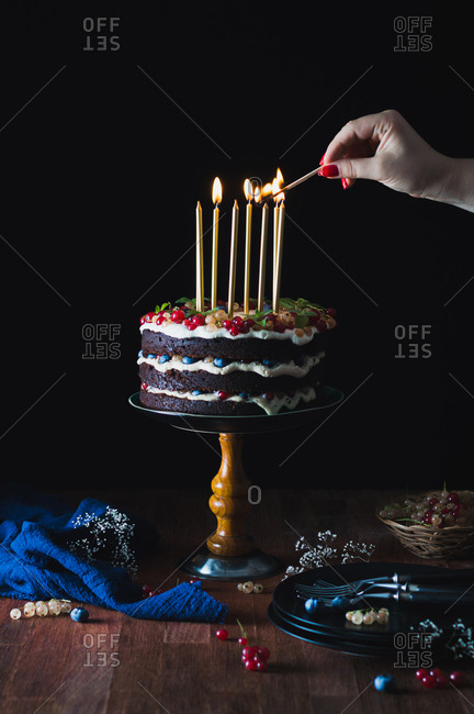 Lighting candles on chocolate berry birthday cake
