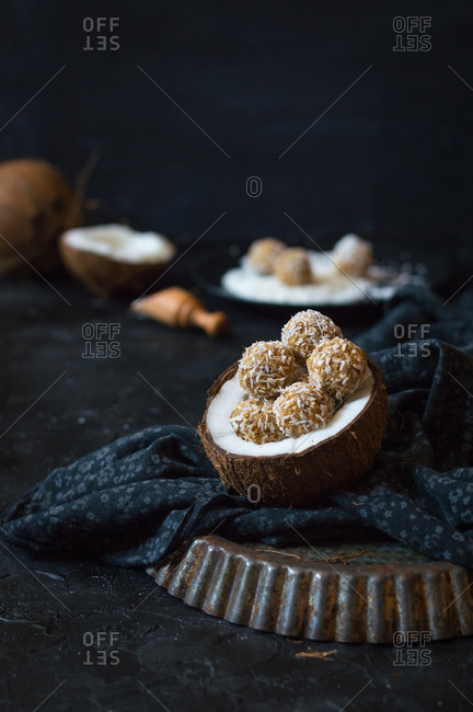 Raw coconut energy balls inside of a halved coconut