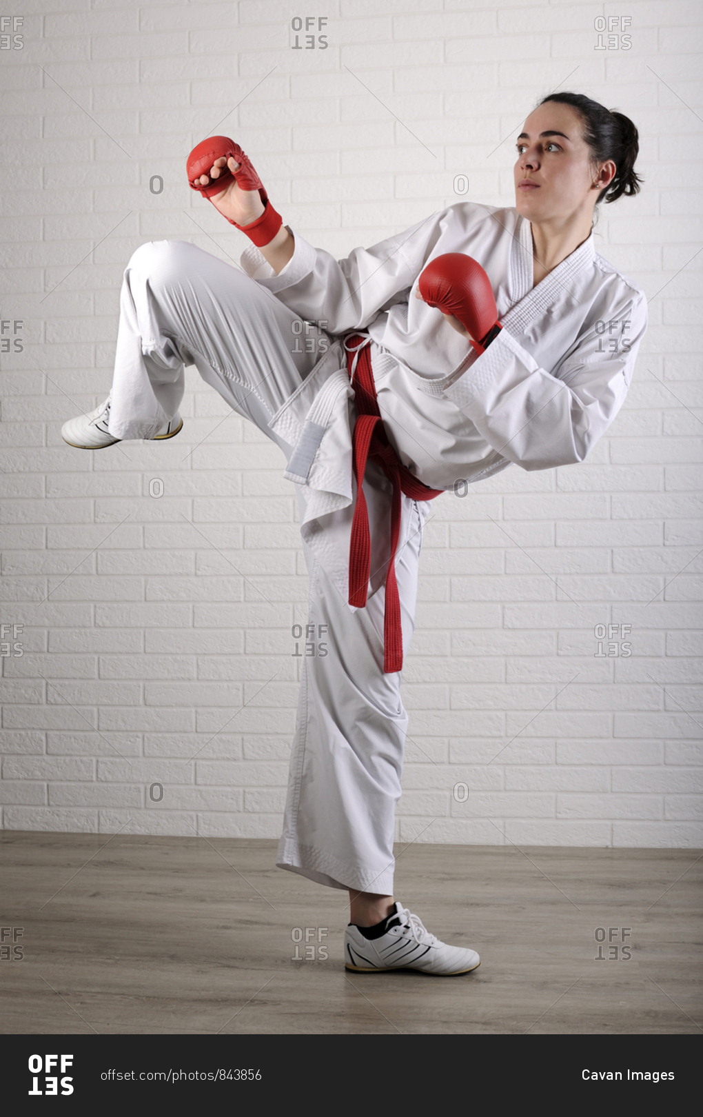 Full length of woman practicing karate against wall on hardwood floor