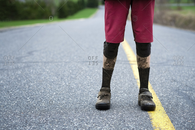 Low section of teenage boy standing with dirty shoes on street