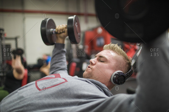 Weightlifter listens to music while training with dumbbells at the gym