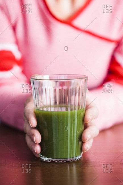 Close-up of woman holding a green juice.