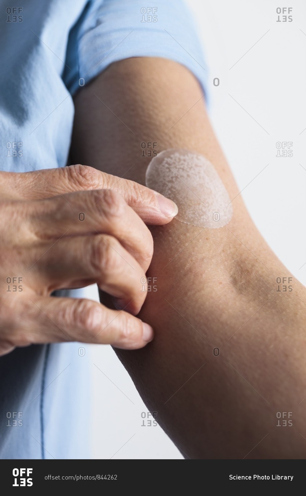 Woman applying a hormone replacement therapy (HRT) patch to her arm.