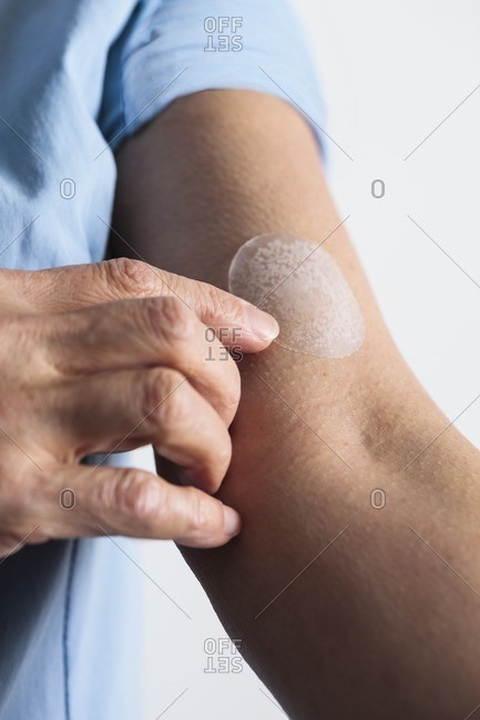 Woman applying a hormone replacement therapy (HRT) patch to her arm.