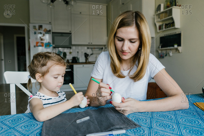 Mother and child decorate an Easter egg. girl with mother to draw egg