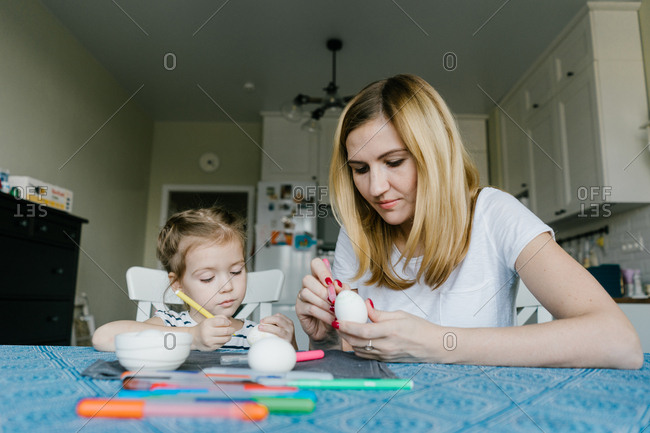 Mother and child decorate an Easter egg. girl with mother to draw egg
