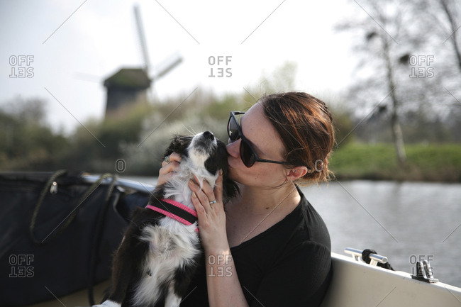 Young woman giving her small dog a kiss on a boat.
