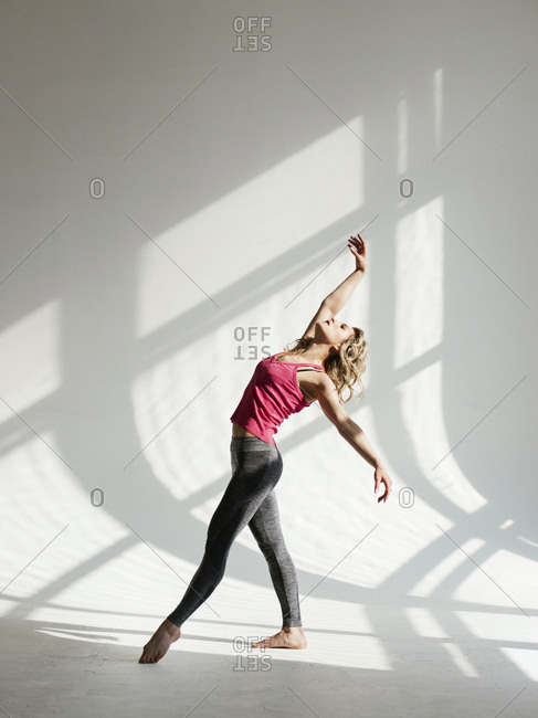 Female dancer dancing against white wall in studio