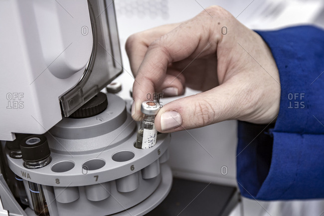 Cropped hand of scientist arranging vials in centrifuge on table at process laboratory