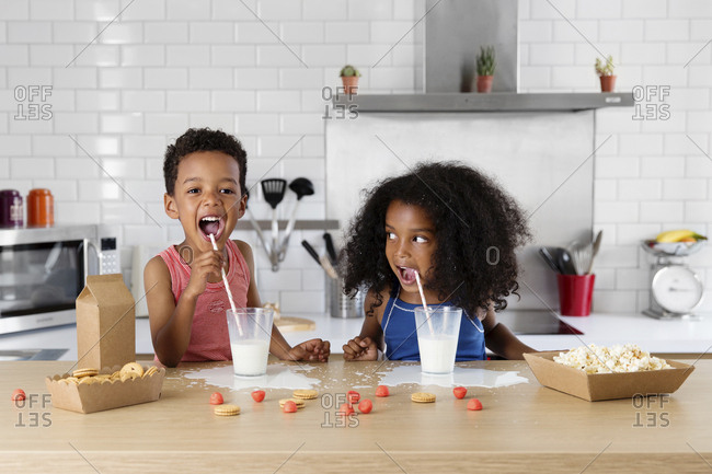 Siblings drinking milk in the kitchen