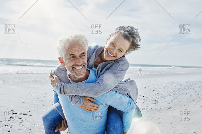 Man giving his wife a piggyback ride on the beach
