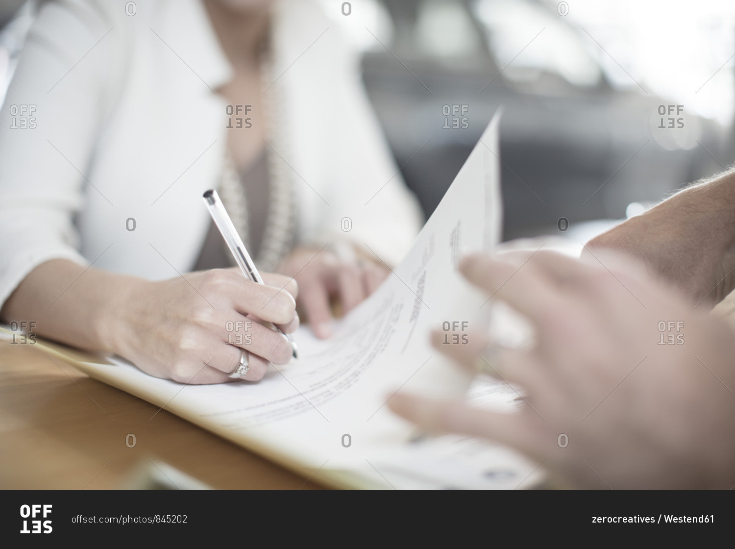 Woman signing contract at desk at car dealership
