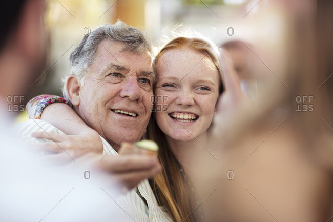 Granddaughter hugging grandfather outdoors