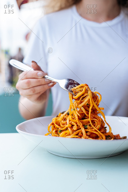 Woman twirling pasta around a fork.