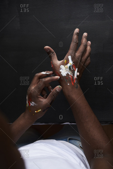 Dirty hands of artist with colorful paints against black background. London- UK.