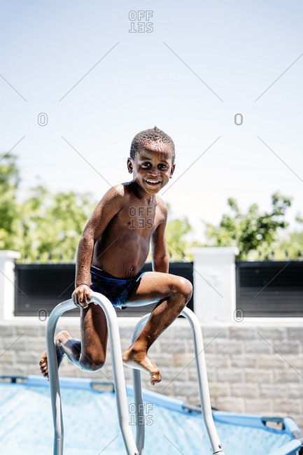 Happy little boy on a ladder of the swimming pool