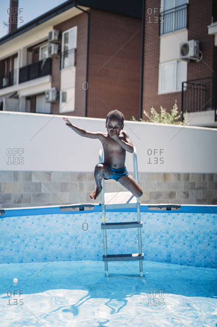 Happy little boy on a ladder of the swimming pool