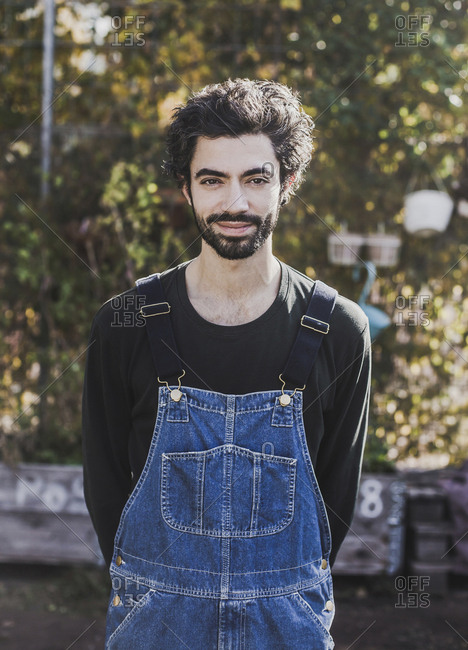 Portrait of smiling man wearing denim dungarees in garden