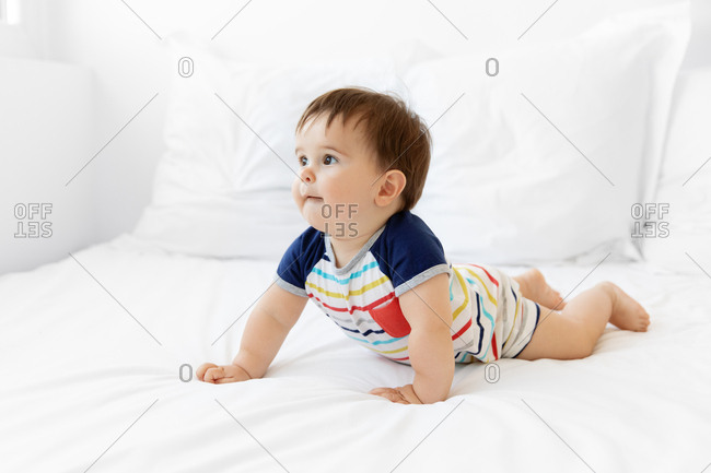 Cute baby lying on tummy on white bed