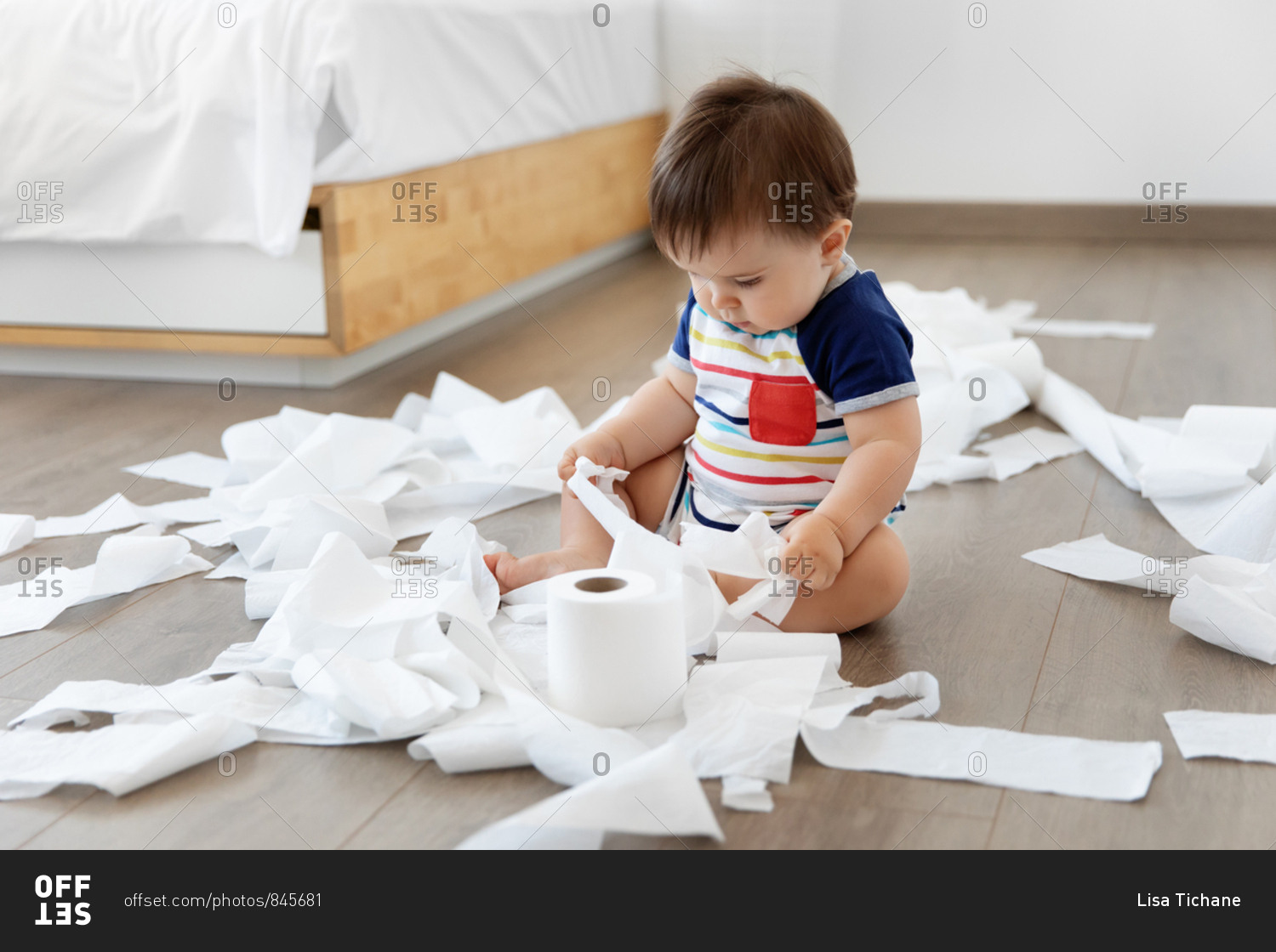 Baby sitting on floor making mess with toilet paper stock photo OFFSET