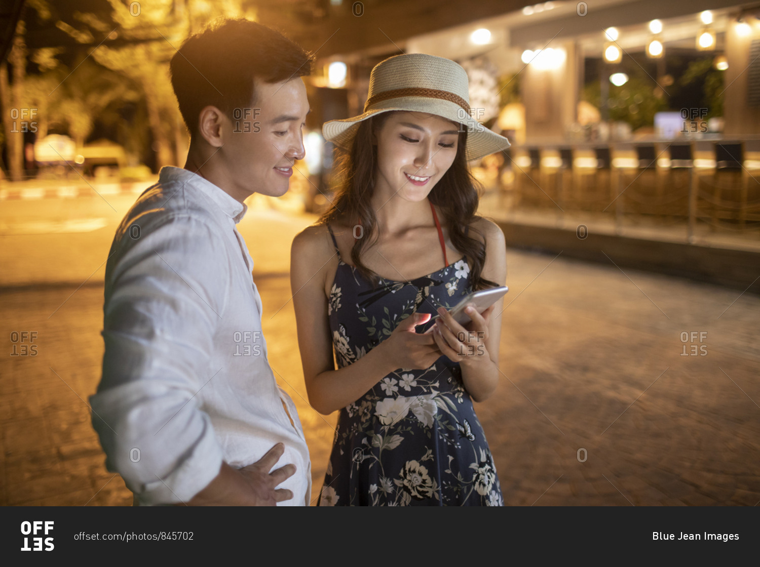 Happy young Chinese couple using smartphone