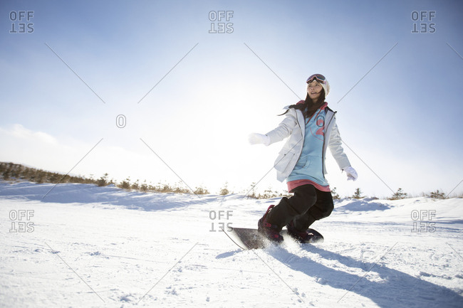 Happy young Chinese woman skiing in ski resort