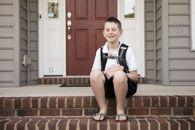Tween Boy With Braces Sits on Brick Front Step, First Day of School