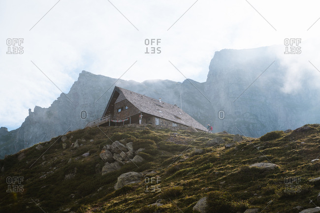 Hiker approaches a mountain hut on a misty day