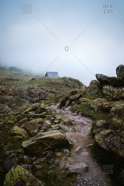 Trail leading to a mountain hut on a foggy day