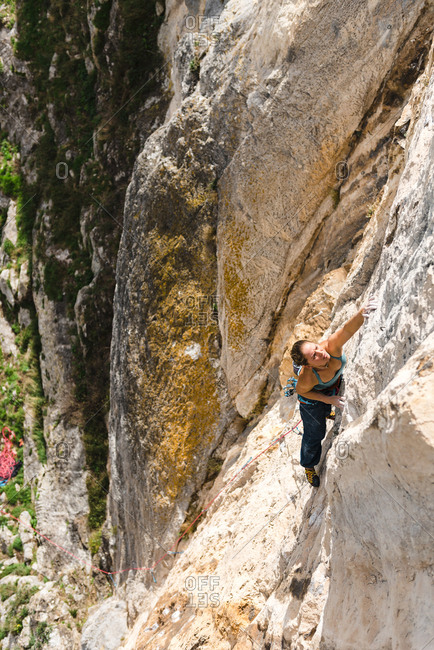 Strong woman rock climber grabbing a ledge in overhanging wall