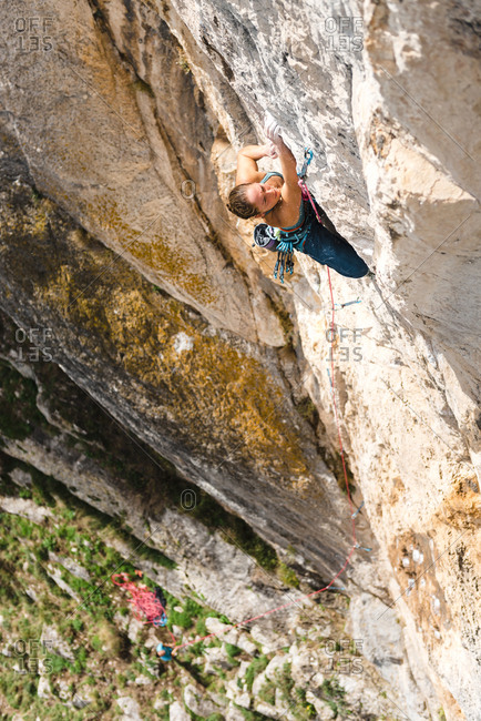 Strong woman rock climber grabbing a ledge in overhanging wall