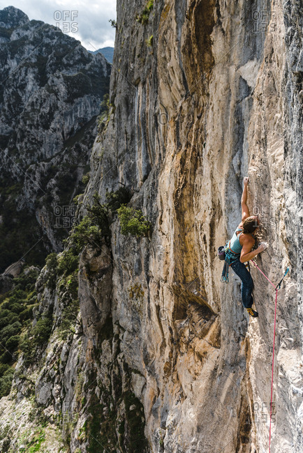 Strong woman rock climber grabbing a ledge in vertical wall