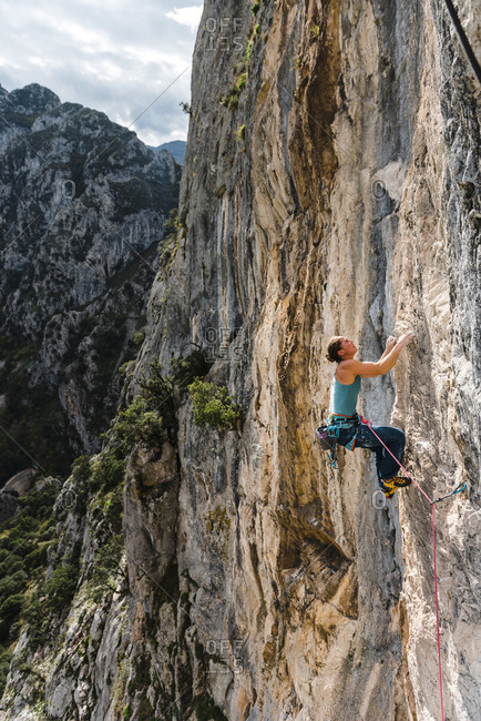 Strong woman rock climber on vertical limestone wall at sunset