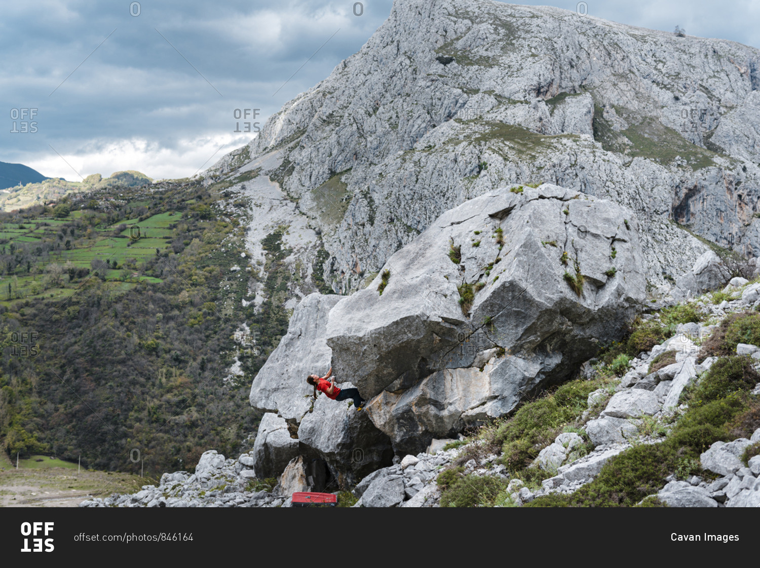 Woman climber trying gray limestone boulder on scenic forest landscape