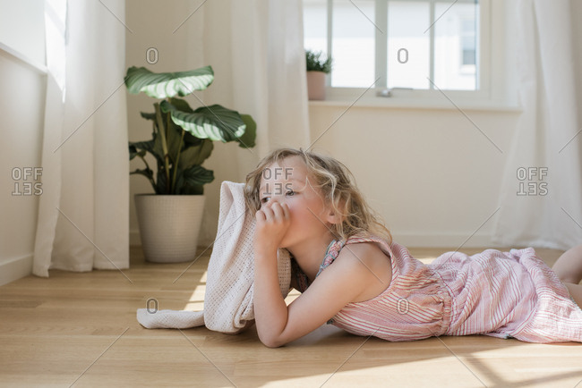 young girl laying down looking tired sucking her thumb