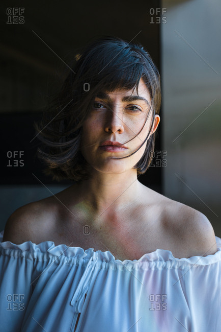 Attractive young brunette woman looking at camera with hair blowing in the wind