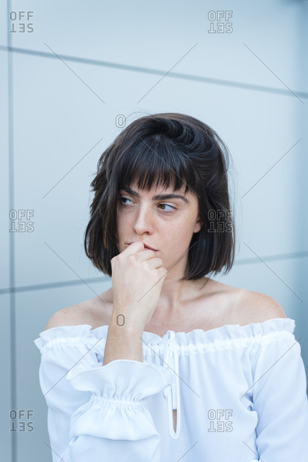 Serious female in trendy blouse looking away in front of gray wall